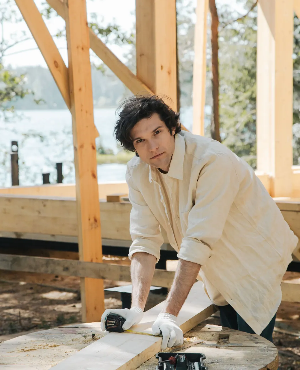 Charpentier en chemise claire ajustant une pièce de bois sur une charpente en construction