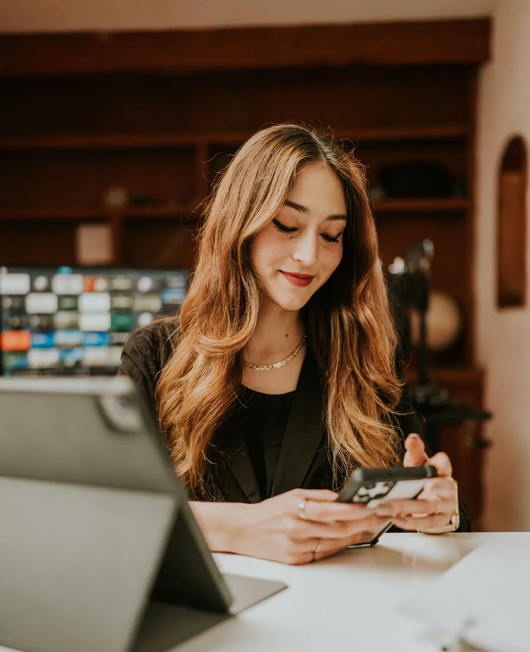 Community manager consultant les réseaux sociaux sur son smartphone devant sa tablette