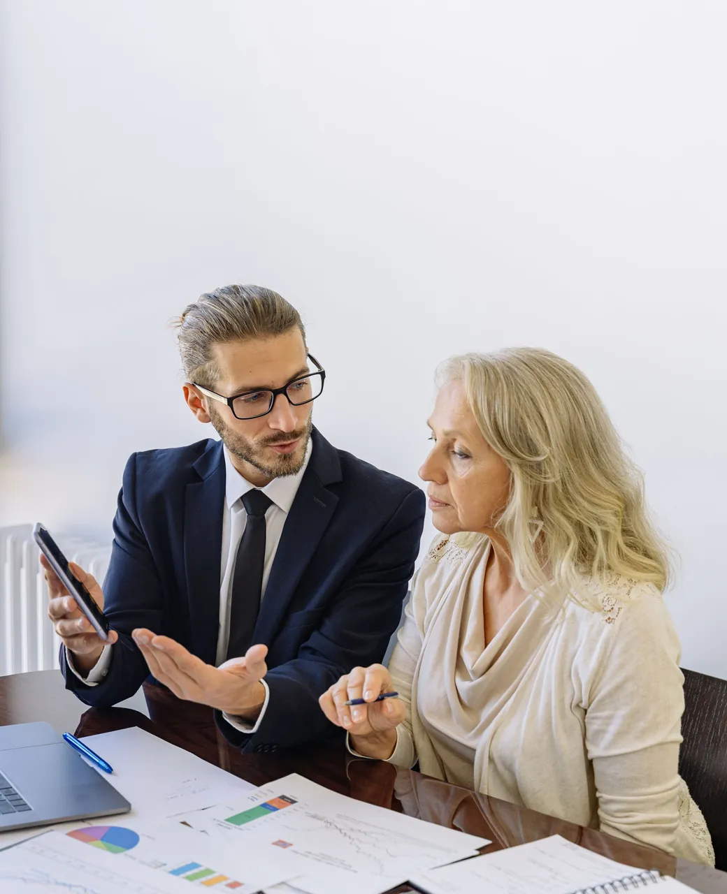 Consultant indépendant commentant des chiffres avec une cliente autour d’un bureau