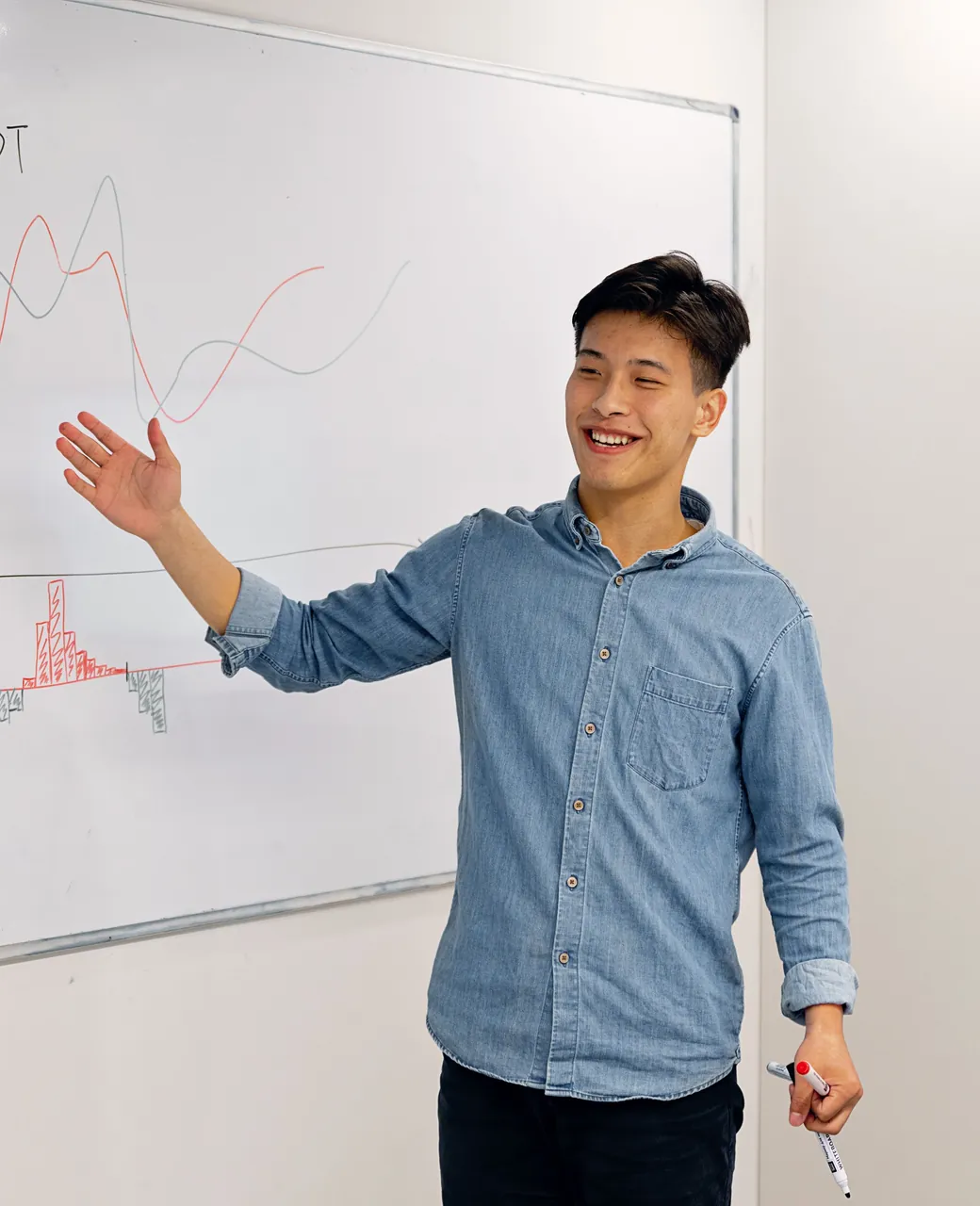 Formateur souriant présentant un schéma sur un tableau blanc devant son groupe