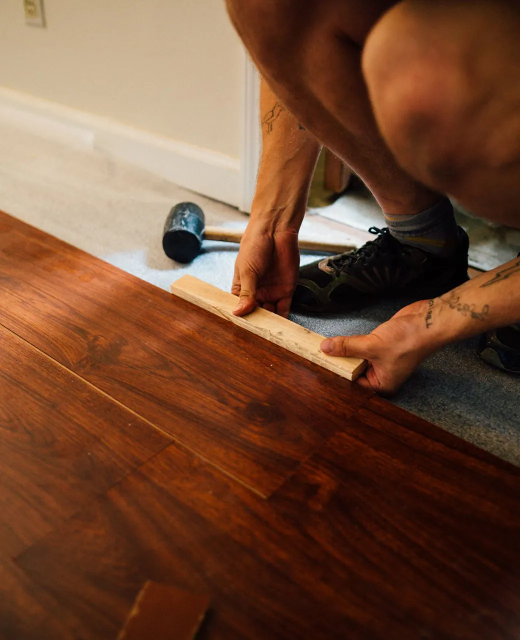 Parqueteur posant des lames de parquet en noyer, maillet posé au sol