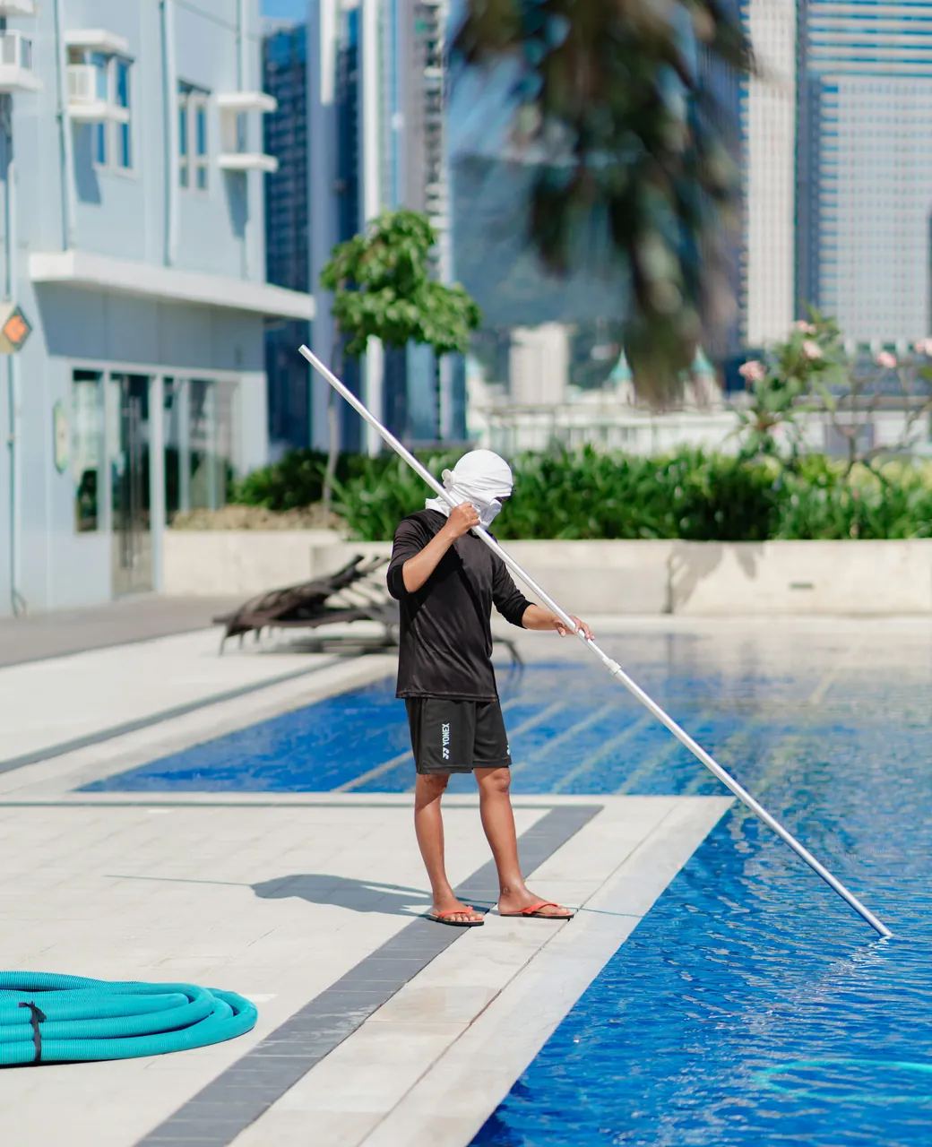 Technicien d’entretien de piscine nettoyant un bassin avec une perche télescopique