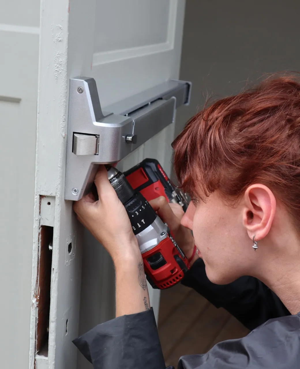 Serrurière installant une serrure de sécurité sur une porte avec une visseuse